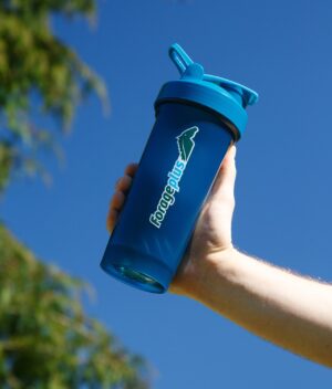 A hand holding the supplement shaker with a blue sky background.