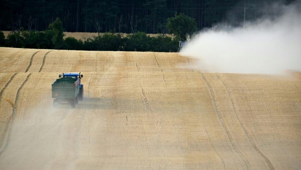 A farmer spraying pesticides in his wheat field.