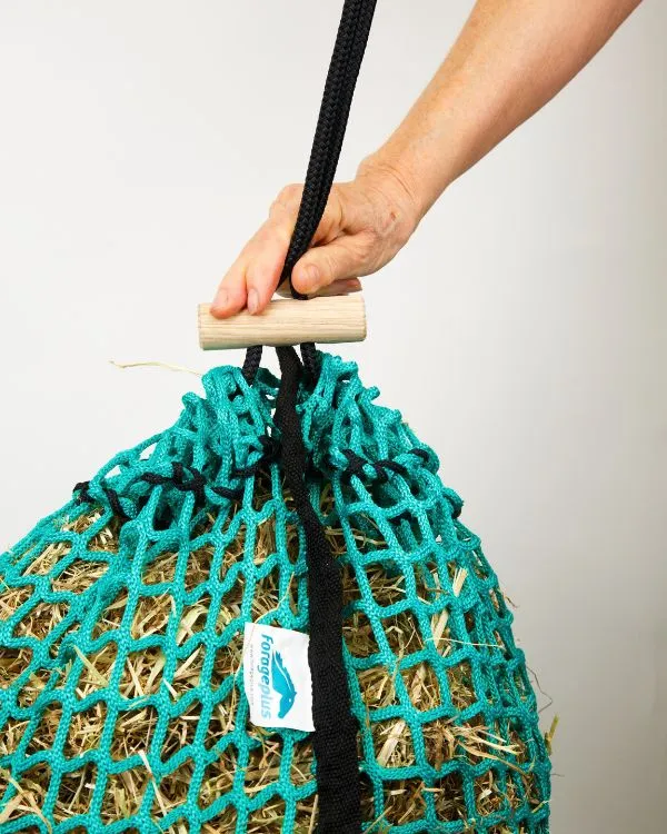Pulling the wooden toggle down to gather and close the top of the hay net