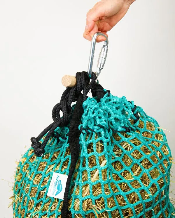 A full Forageplus knotless slow feeder hay net ready to hang by its screw-gate carabiner